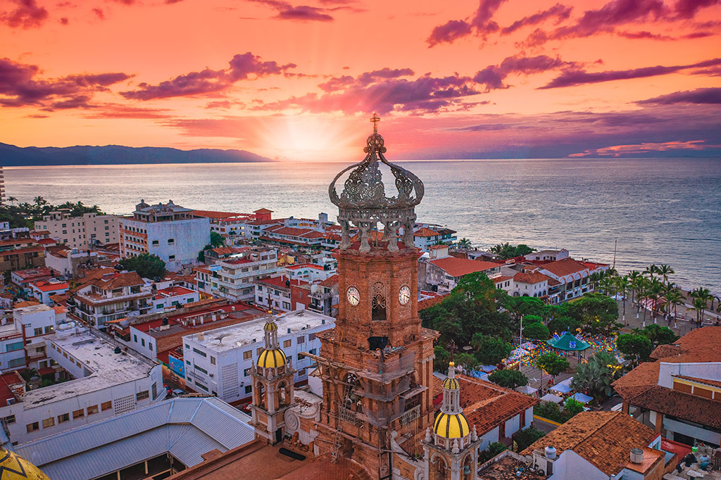 An amazing sight of the Church of Our Lady of Guadalupe in Puerto Vallarta at the sunset with the colorful sky and the Pacific Ocean.